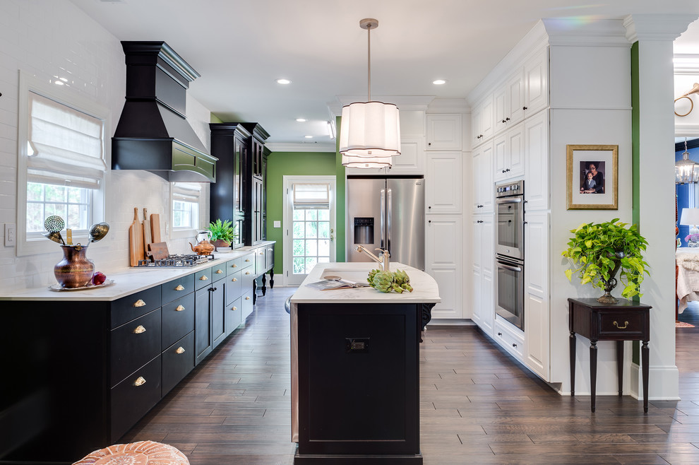 Mid-sized trendy u-shaped medium tone wood floor and brown floor kitchen photo in Austin with an undermount sink, shaker cabinets, dark wood cabinets, marble countertops, white backsplash, subway tile backsplash, stainless steel appliances and an island