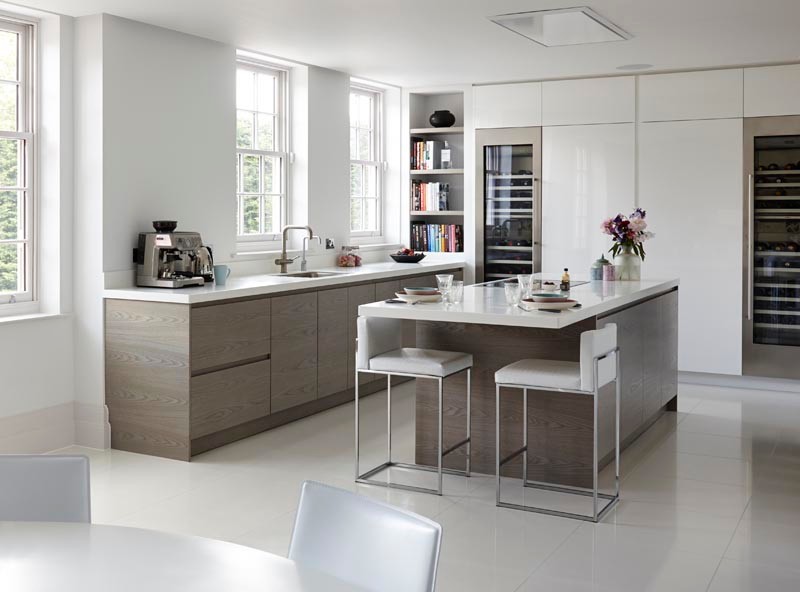 Large minimalist u-shaped ceramic tile and white floor open concept kitchen photo in London with an integrated sink, flat-panel cabinets, white cabinets, solid surface countertops, paneled appliances, an island and white countertops
