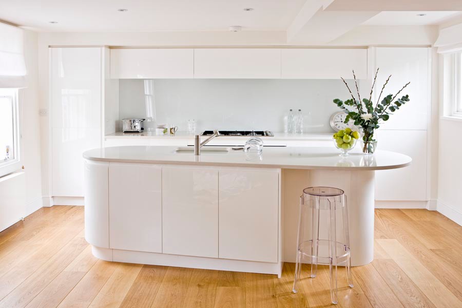 Example of a mid-sized trendy galley ceramic tile open concept kitchen design in London with recessed-panel cabinets, white cabinets, quartzite countertops, white backsplash, ceramic backsplash, stainless steel appliances, an island and white countertops