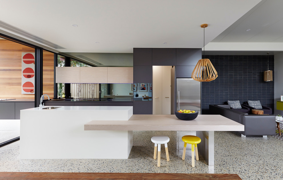 Modern inredning av ett kök, med en undermonterad diskho, släta luckor, grå skåp, glaspanel som stänkskydd, rostfria vitvaror och en köksö