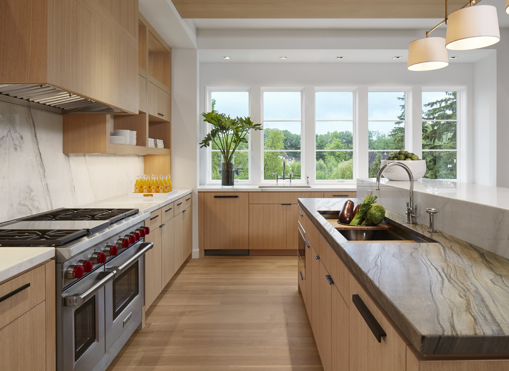 Moderne Küche in L-Form mit Unterbauwaschbecken, flächenbündigen Schrankfronten, hellbraunen Holzschränken, Küchenrückwand in Weiß, Küchengeräten aus Edelstahl, braunem Holzboden und Kücheninsel in Minneapolis