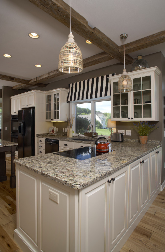 Foto di una cucina rustica con lavello sottopiano, ante con bugna sagomata, ante bianche, top in granito, elettrodomestici neri e parquet chiaro