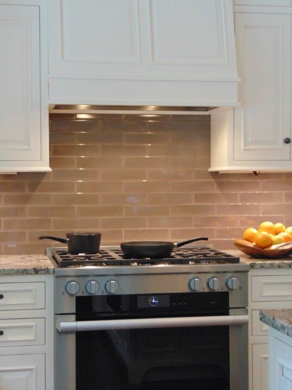 Exempel på ett lantligt kök och matrum, med luckor med profilerade fronter, vita skåp, granitbänkskiva, beige stänkskydd, stänkskydd i glaskakel, integrerade vitvaror, mörkt trägolv och en köksö
