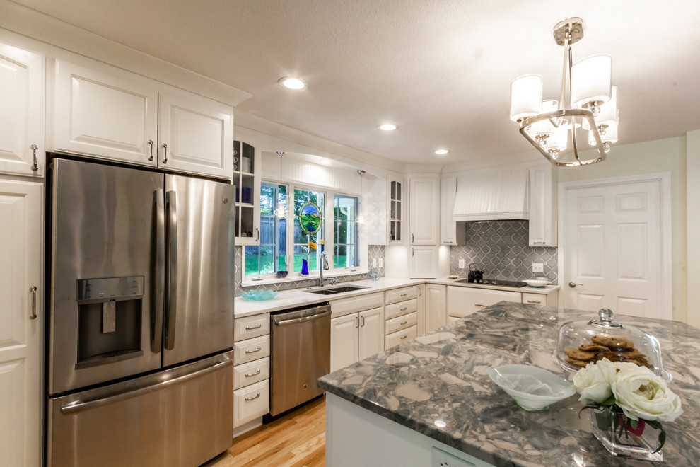 Inspiration for a large coastal u-shaped light wood floor and brown floor enclosed kitchen remodel in Other with a double-bowl sink, raised-panel cabinets, white cabinets, granite countertops, blue backsplash, ceramic backsplash, stainless steel appliances, an island and white countertops