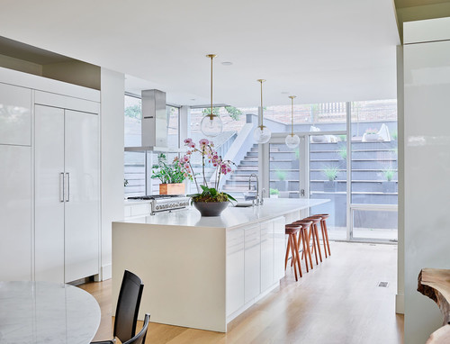 Modern white kitchen with frameless RTA cabinets, large island, pendant lights, and natural light—Canadian kitchen cabinet maintenance inspiration