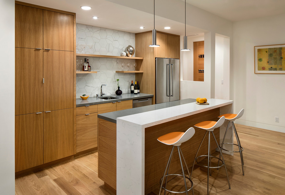 Medium sized contemporary galley open plan kitchen in San Francisco with a submerged sink, flat-panel cabinets, medium wood cabinets, engineered stone countertops, white splashback, porcelain splashback, stainless steel appliances, light hardwood flooring, an island and beige floors.