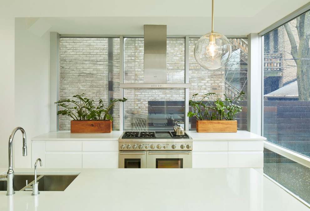 Immagine di una grande cucina design con lavello a doppia vasca, ante bianche, top in superficie solida, elettrodomestici in acciaio inossidabile e parquet chiaro
