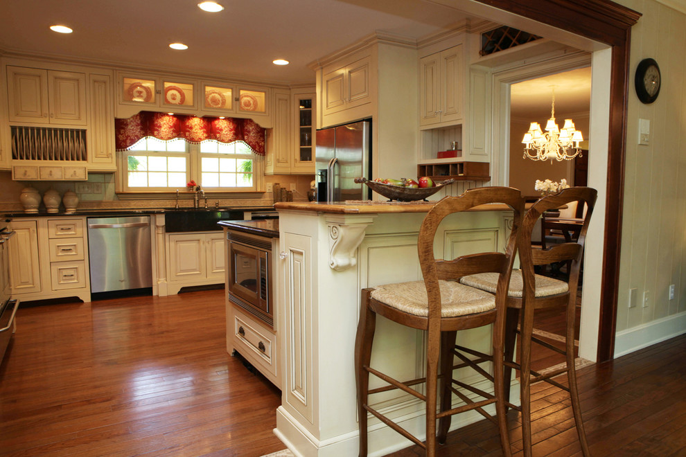 Immagine di una cucina a L country con ante bianche, elettrodomestici in acciaio inossidabile e pavimento in legno massello medio