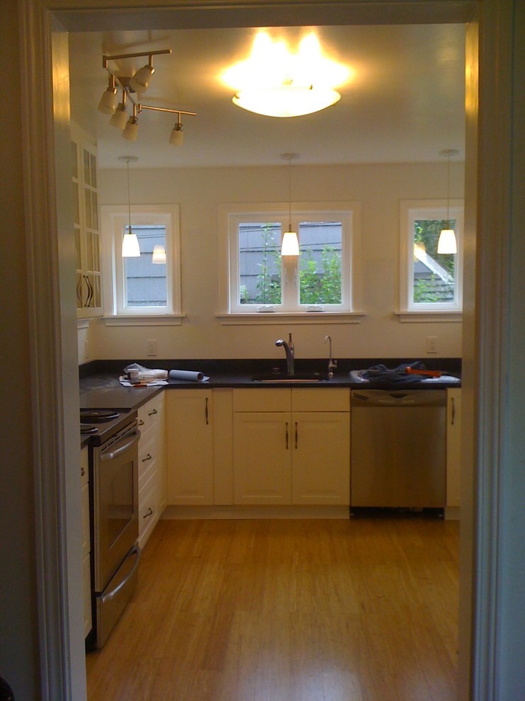 Mid-sized l-shaped bamboo floor enclosed kitchen photo in Seattle with quartz countertops and stainless steel appliances