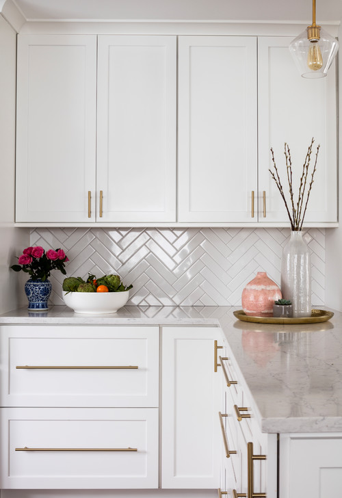 This kitchen is a delight. It's white, but not too stark—it has a warm glow that makes it feel welcoming and inviting. The brass hardware adds a touch of class without being overbearing, while the veined countertop gives the room a little bit of depth.