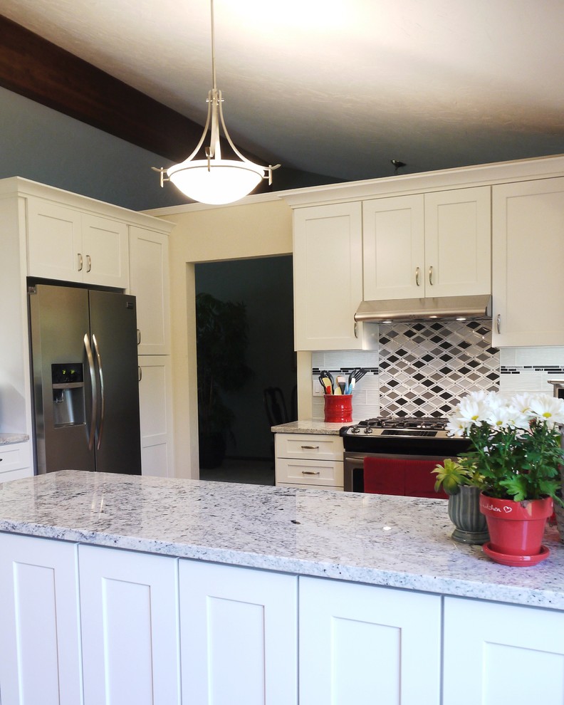 Eat-in kitchen - mid-sized transitional u-shaped medium tone wood floor eat-in kitchen idea in Grand Rapids with shaker cabinets, white cabinets, granite countertops, multicolored backsplash, glass tile backsplash, stainless steel appliances, a peninsula and a double-bowl sink