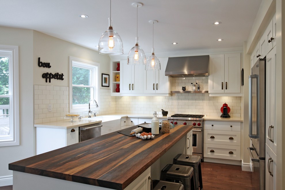 This is an example of a small bohemian l-shaped kitchen in Toronto with a belfast sink, wood worktops, white splashback, stainless steel appliances, medium hardwood flooring and an island.
