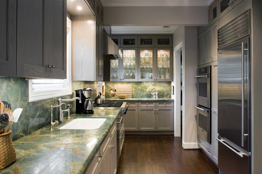 Mid-sized trendy galley medium tone wood floor enclosed kitchen photo in Houston with an undermount sink, recessed-panel cabinets, gray cabinets, marble countertops, green backsplash, stone slab backsplash, stainless steel appliances and no island