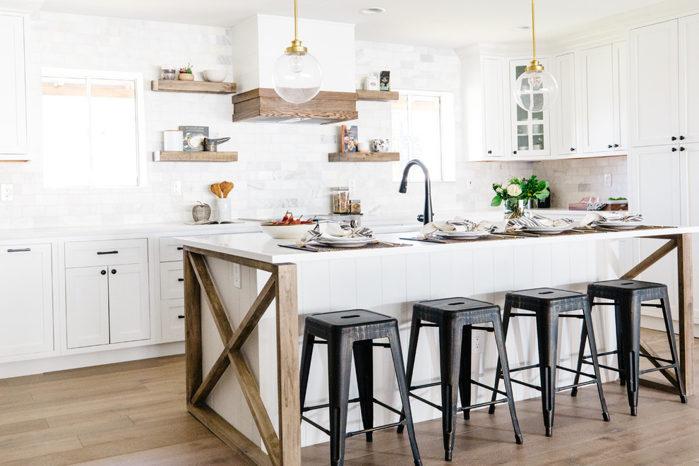 Inspiration for a large farmhouse u-shaped medium tone wood floor and brown floor open concept kitchen remodel in Phoenix with a double-bowl sink, recessed-panel cabinets, white cabinets, quartz countertops, white backsplash, marble backsplash, stainless steel appliances and an island