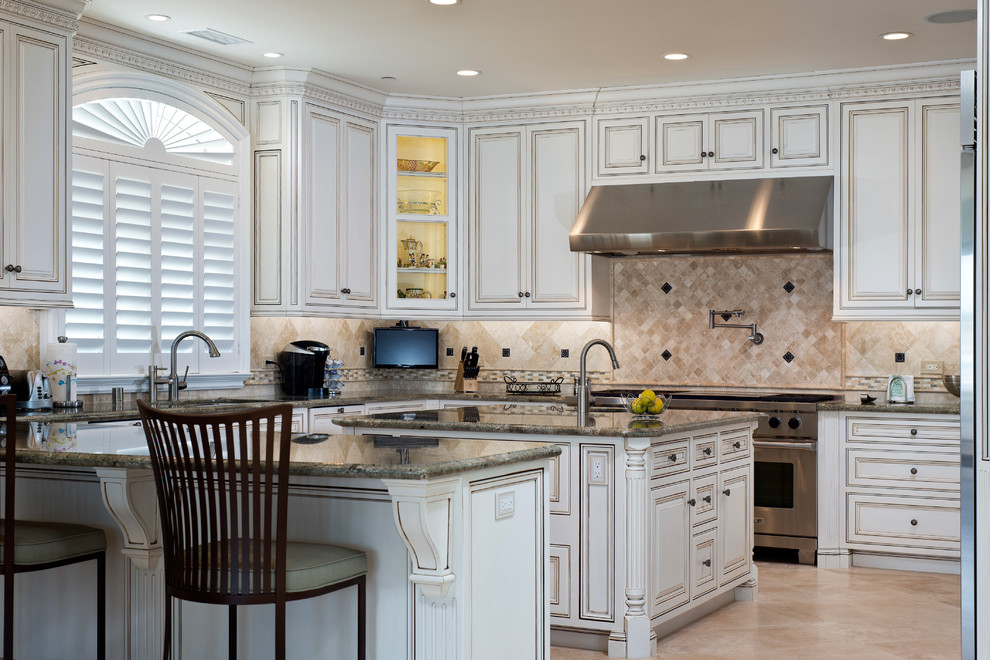 Example of a large classic u-shaped marble floor and beige floor eat-in kitchen design in Orange County with an undermount sink, raised-panel cabinets, white cabinets, granite countertops, beige backsplash, stone tile backsplash, stainless steel appliances and an island