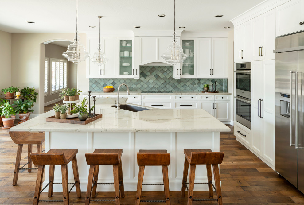 Bild på ett mellanstort vintage vit vitt kök, med en undermonterad diskho, skåp i shakerstil, vita skåp, bänkskiva i kvartsit, blått stänkskydd, stänkskydd i terrakottakakel, rostfria vitvaror, mörkt trägolv, en köksö och brunt golv