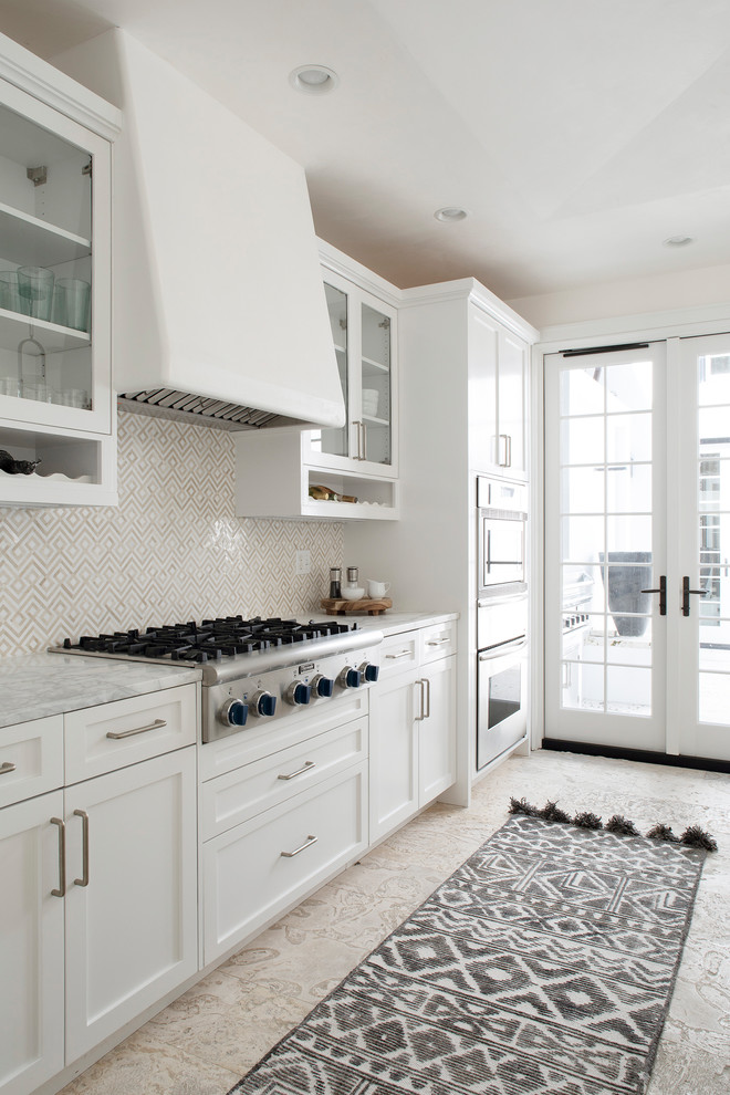 Maritim inredning av ett stort vit linjärt vitt kök och matrum, med en enkel diskho, skåp i shakerstil, vita skåp, marmorbänkskiva, vitt stänkskydd, stänkskydd i marmor, rostfria vitvaror och en köksö