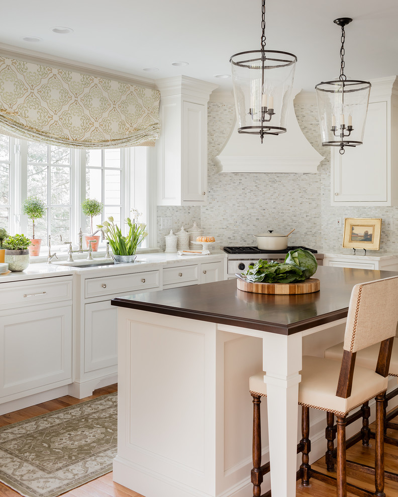 Inredning av ett klassiskt mellanstort kök, med en undermonterad diskho, vita skåp, marmorbänkskiva, stänkskydd i mosaik, en köksö, luckor med infälld panel, flerfärgad stänkskydd, rostfria vitvaror och mellanmörkt trägolv