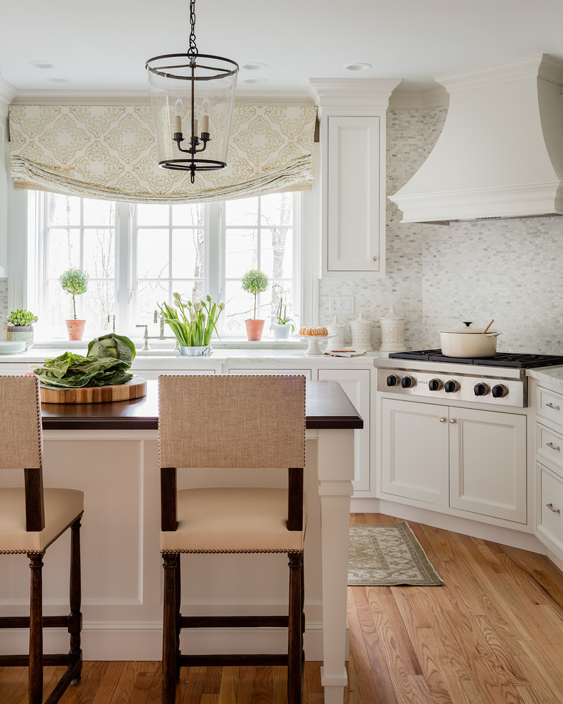 Mittelgroße Klassische Küche mit weißen Schränken, Marmor-Arbeitsplatte, Rückwand aus Mosaikfliesen, Kücheninsel, Schrankfronten mit vertiefter Füllung, bunter Rückwand, Küchengeräten aus Edelstahl und braunem Holzboden in Boston