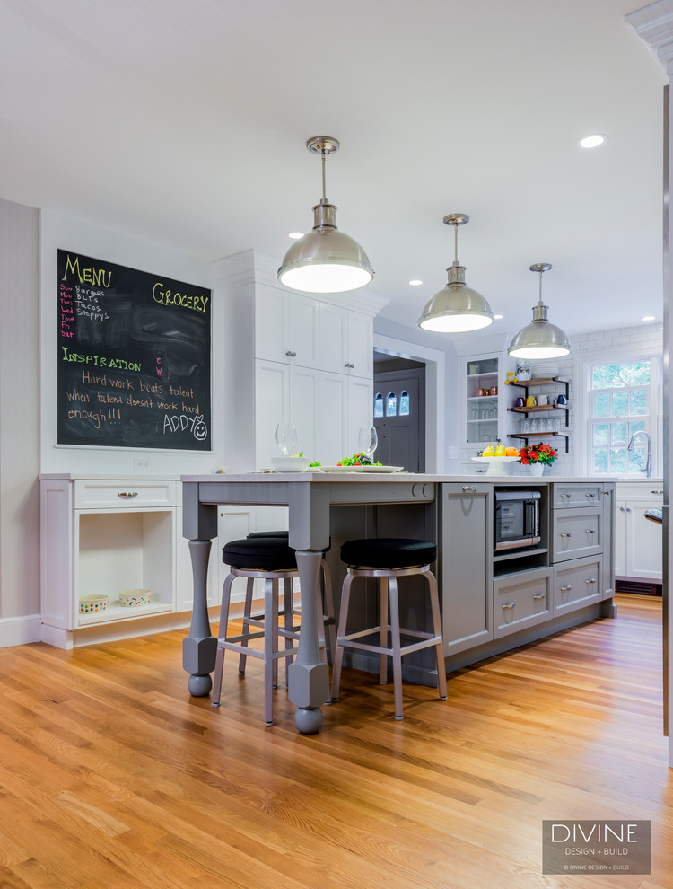 Exempel på ett mellanstort eklektiskt kök, med en undermonterad diskho, skåp i shakerstil, vita skåp, bänkskiva i kvarts, vitt stänkskydd, stänkskydd i tunnelbanekakel, rostfria vitvaror, mellanmörkt trägolv, en köksö och brunt golv