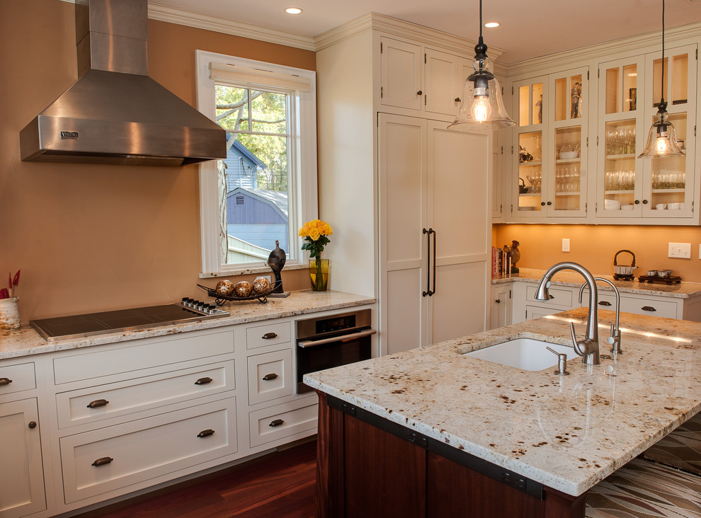 Imagen de cocina clásica de tamaño medio con fregadero bajoencimera, armarios estilo shaker, electrodomésticos con paneles, encimera de granito, puertas de armario blancas, suelo de madera oscura y una isla