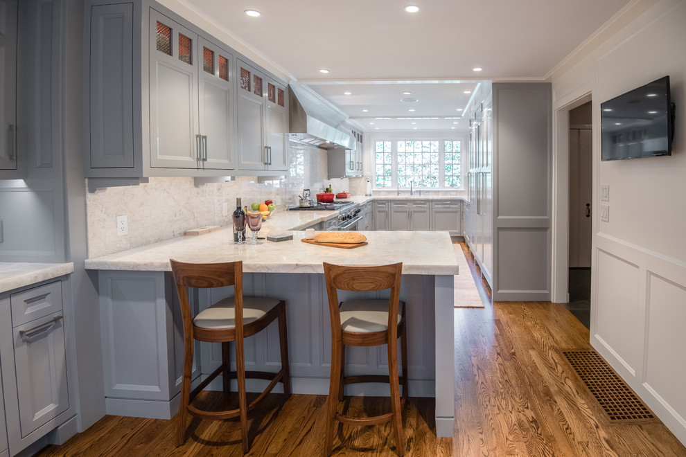 Example of a mid-sized transitional u-shaped medium tone wood floor enclosed kitchen design in Boston with an undermount sink, shaker cabinets, gray cabinets, quartzite countertops, white backsplash, stone slab backsplash, stainless steel appliances and a peninsula