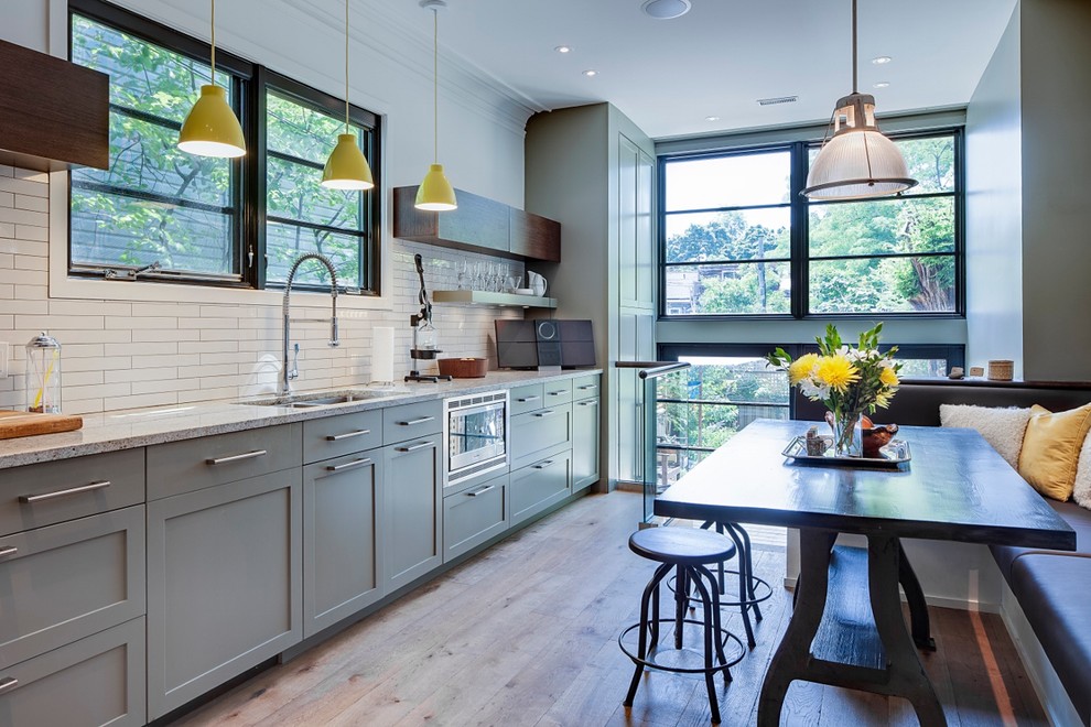 Foto på ett mellanstort funkis kök, med granitbänkskiva, en undermonterad diskho, skåp i shakerstil, gröna skåp, vitt stänkskydd, stänkskydd i porslinskakel, rostfria vitvaror och ljust trägolv