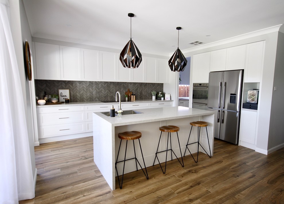 Exempel på ett stort modernt grå grått kök, med en nedsänkt diskho, skåp i shakerstil, vita skåp, bänkskiva i kvarts, grått stänkskydd, stänkskydd i keramik, rostfria vitvaror, mellanmörkt trägolv, en köksö och brunt golv