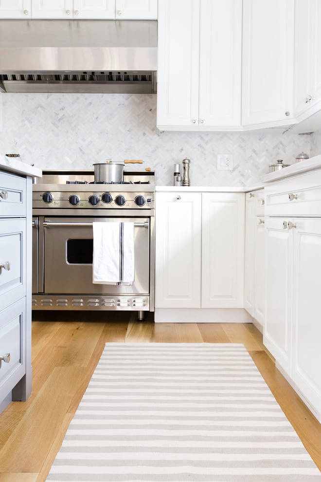Foto di una cucina moderna con lavello a vasca singola, top in superficie solida, paraspruzzi con piastrelle in pietra, elettrodomestici in acciaio inossidabile e parquet chiaro