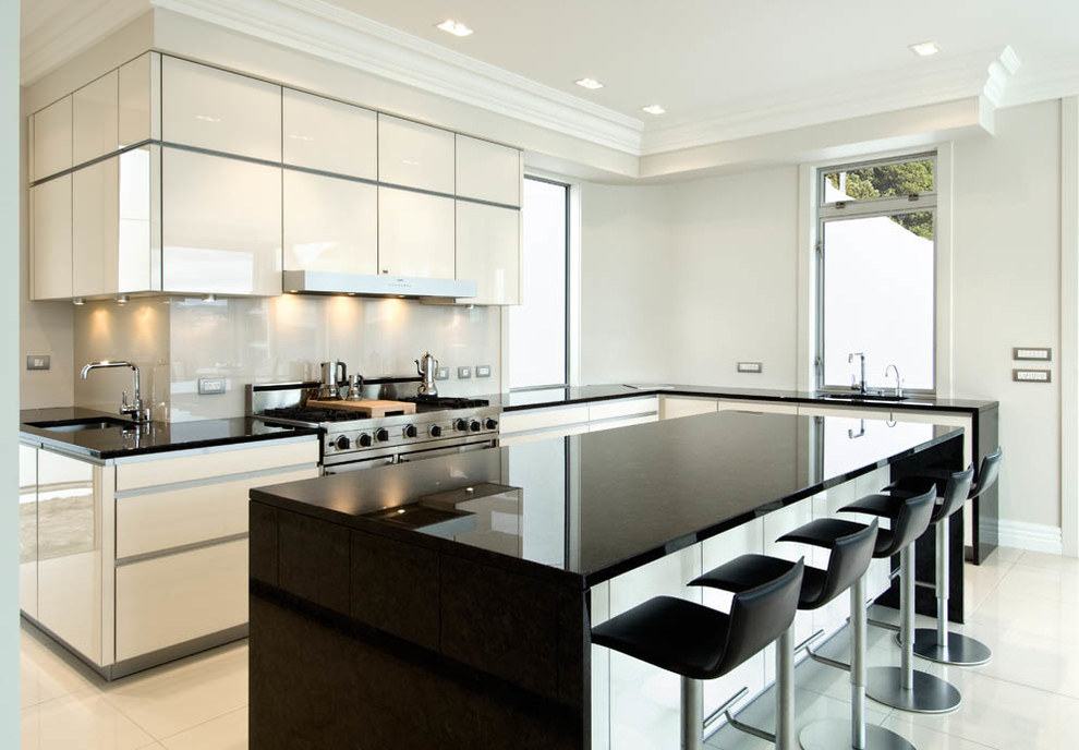 Moderne Wohnküche mit Waschbecken, weißen Schränken, Granit-Arbeitsplatte, Küchenrückwand in Weiß, Glasrückwand, bunten Elektrogeräten, Keramikboden und Kücheninsel in Wellington