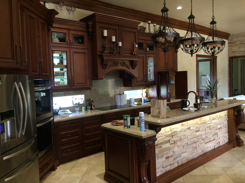 Bild på ett stort medelhavsstil kök, med en enkel diskho, luckor med upphöjd panel, bruna skåp, bänkskiva i kvarts, beige stänkskydd, stänkskydd i stenkakel, rostfria vitvaror, kalkstensgolv och en köksö