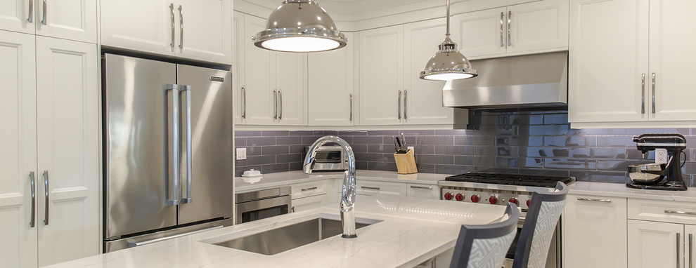 Immagine di una cucina moderna di medie dimensioni con lavello sottopiano, ante in stile shaker, ante bianche, paraspruzzi grigio, paraspruzzi con piastrelle di vetro e elettrodomestici in acciaio inossidabile
