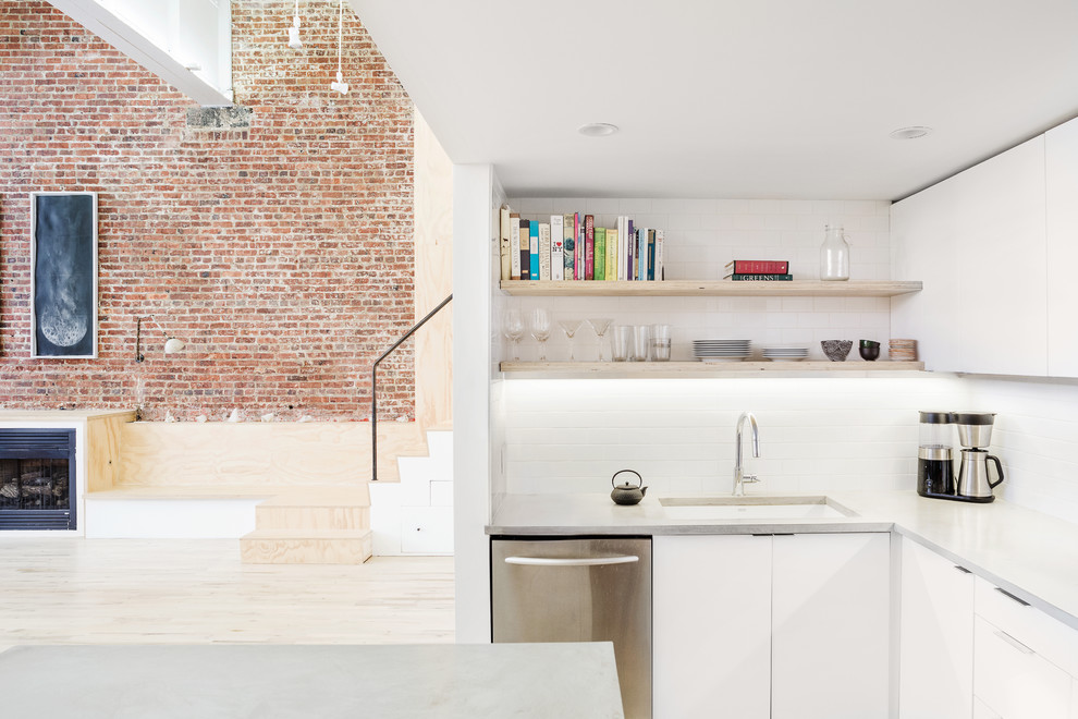 Inspiration for a medium sized urban l-shaped open plan kitchen in New York with a submerged sink, flat-panel cabinets, white cabinets, concrete worktops, white splashback, metro tiled splashback, stainless steel appliances, light hardwood flooring and an island.