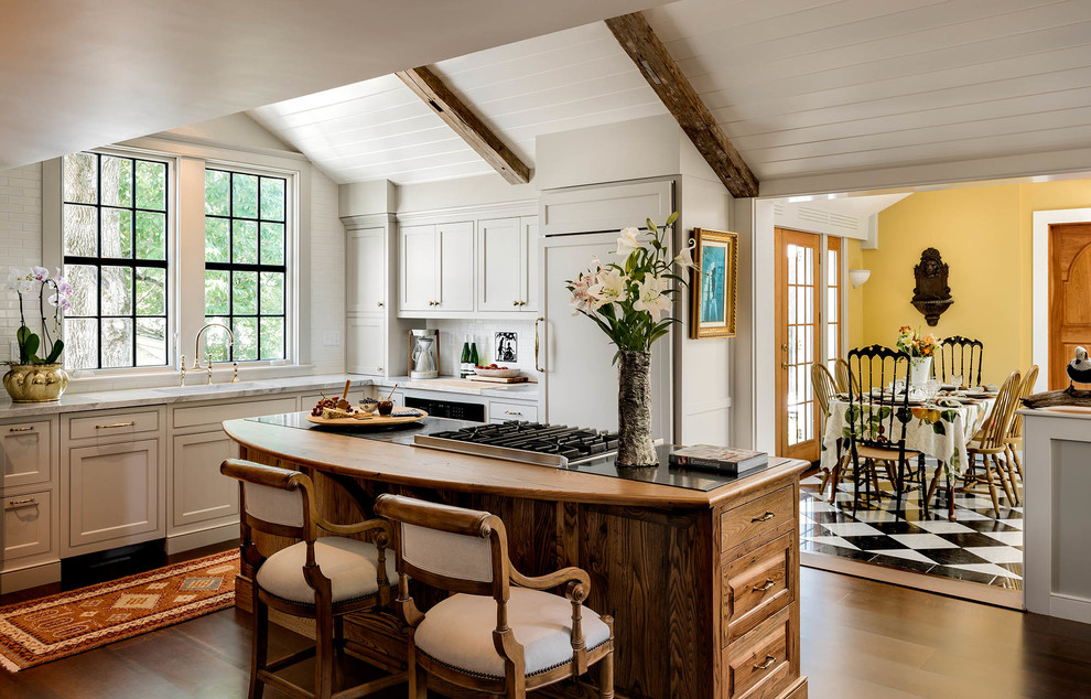 Medium sized country kitchen/diner in Portland Maine with shaker cabinets, white cabinets, white splashback, integrated appliances, dark hardwood flooring and an island.