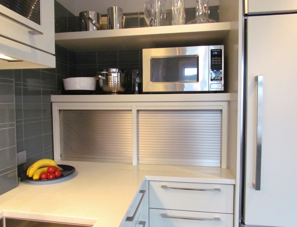 Inredning av ett modernt mellanstort kök, med en undermonterad diskho, släta luckor, vita skåp, bänkskiva i kvarts, grått stänkskydd, stänkskydd i glaskakel, integrerade vitvaror, ljust trägolv, en köksö och brunt golv
