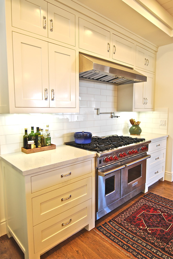 Foto de cocina costera con electrodomésticos de acero inoxidable, encimera de cuarzo compacto y salpicadero blanco