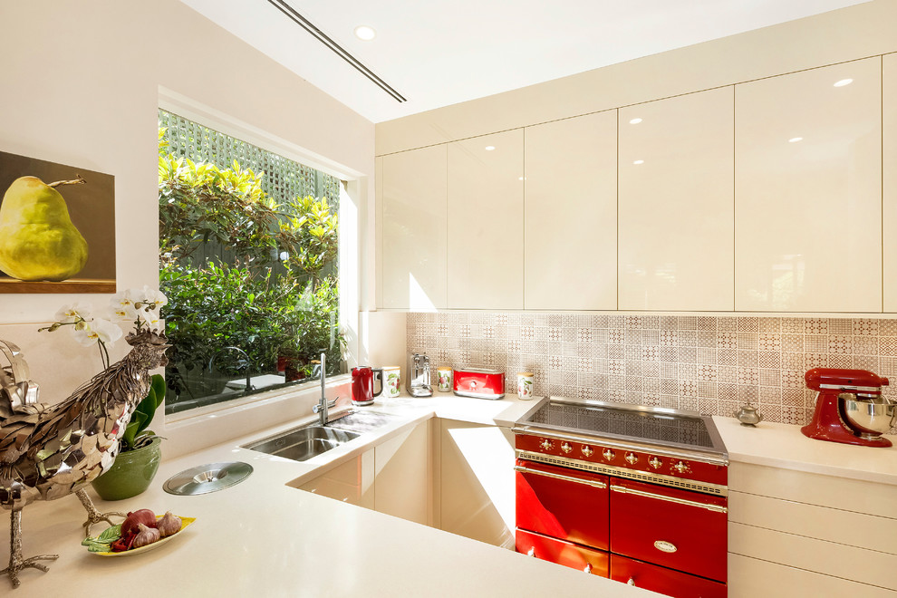 Immagine di una cucina design di medie dimensioni con lavello sottopiano, ante beige, paraspruzzi multicolore, elettrodomestici colorati, parquet chiaro e penisola