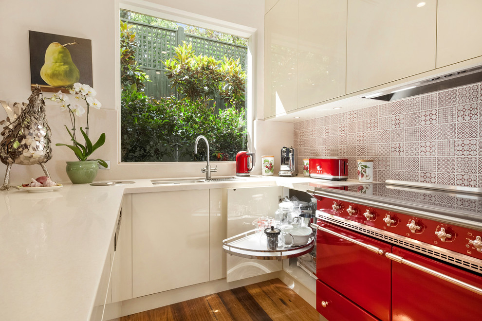 Modern inredning av ett mellanstort kök, med en undermonterad diskho, beige skåp, flerfärgad stänkskydd, färgglada vitvaror, ljust trägolv och en halv köksö