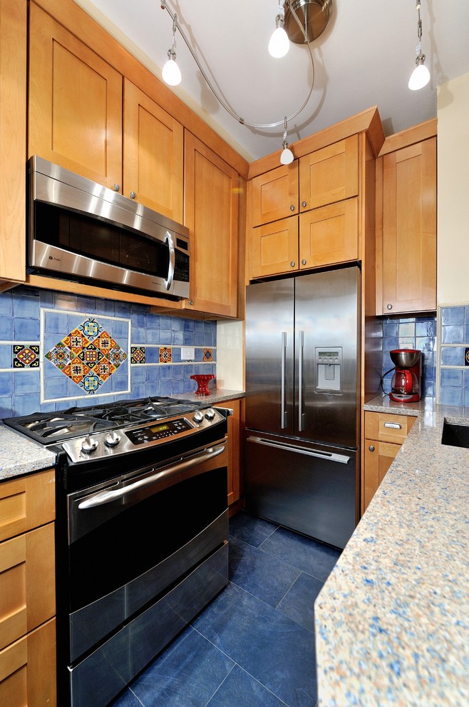 Example of a small tuscan u-shaped porcelain tile enclosed kitchen design in New York with a single-bowl sink, raised-panel cabinets, light wood cabinets, blue backsplash, ceramic backsplash, stainless steel appliances and recycled glass countertops