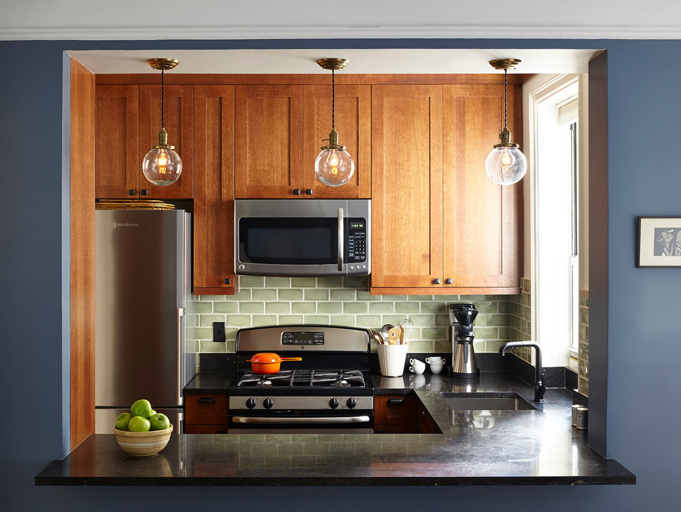 Bild på ett avskilt, litet amerikanskt u-kök, med en undermonterad diskho, skåp i shakerstil, grönt stänkskydd, stänkskydd i keramik, rostfria vitvaror, skåp i mellenmörkt trä och bänkskiva i täljsten