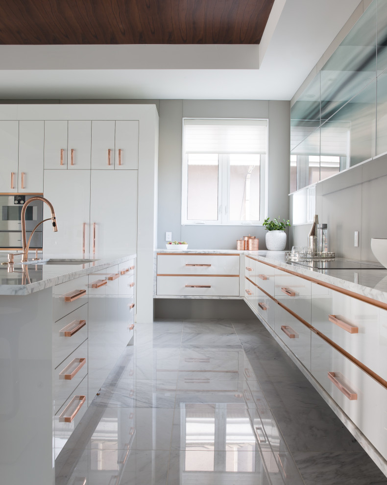 Foto på ett funkis vit l-kök, med en undermonterad diskho, släta luckor, vita skåp, en köksö och grått golv