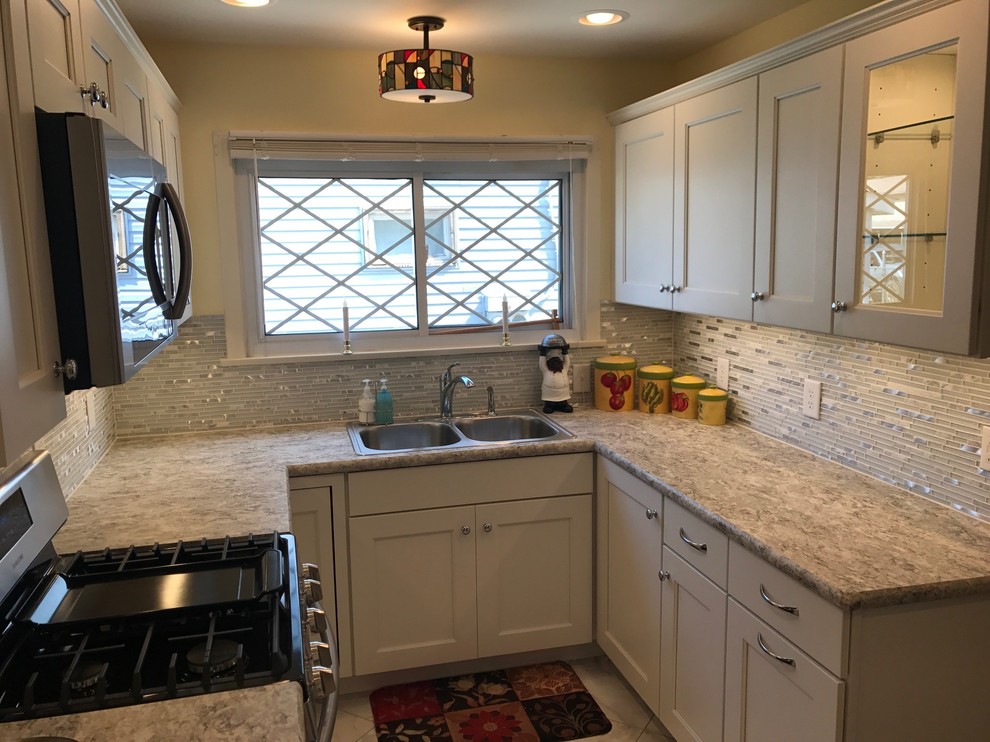 Enclosed kitchen - small transitional u-shaped limestone floor and gray floor enclosed kitchen idea in Other with a drop-in sink, recessed-panel cabinets, white cabinets, laminate countertops, white backsplash, mosaic tile backsplash, stainless steel appliances and no island