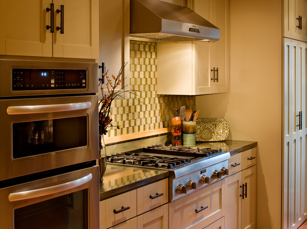 Ejemplo de cocina clásica con electrodomésticos de acero inoxidable, armarios estilo shaker, puertas de armario de madera clara y salpicadero multicolor