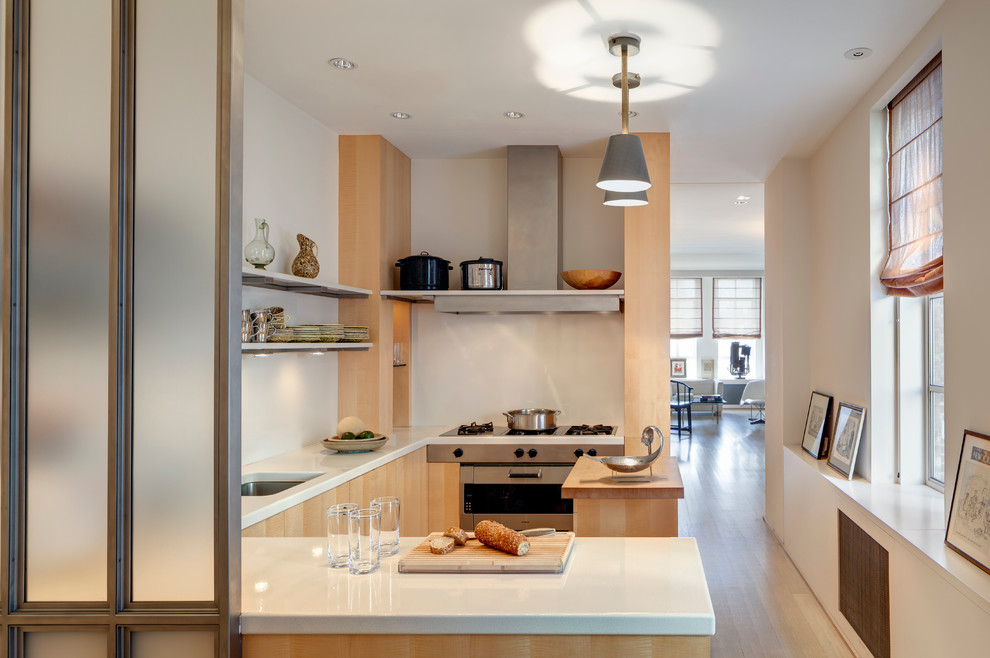 This is an example of a small traditional grey and cream u-shaped enclosed kitchen in New York with a submerged sink, open cabinets, stainless steel appliances, light hardwood flooring, a breakfast bar, light wood cabinets and composite countertops.