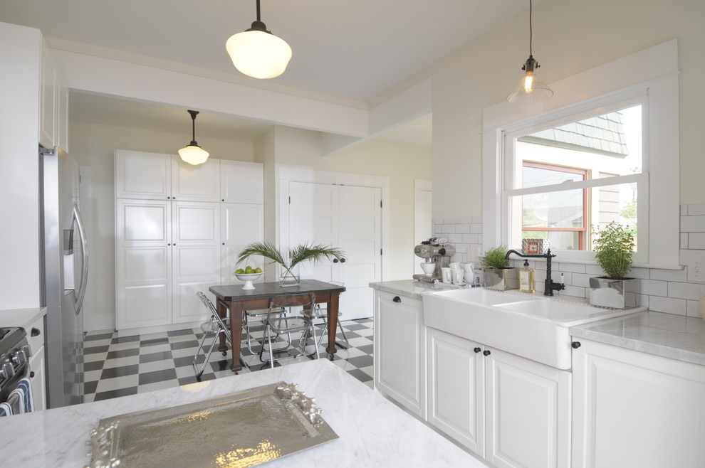 Example of a large arts and crafts u-shaped ceramic tile eat-in kitchen design in Los Angeles with a peninsula, raised-panel cabinets, white cabinets, marble countertops, white backsplash, subway tile backsplash, paneled appliances and a farmhouse sink