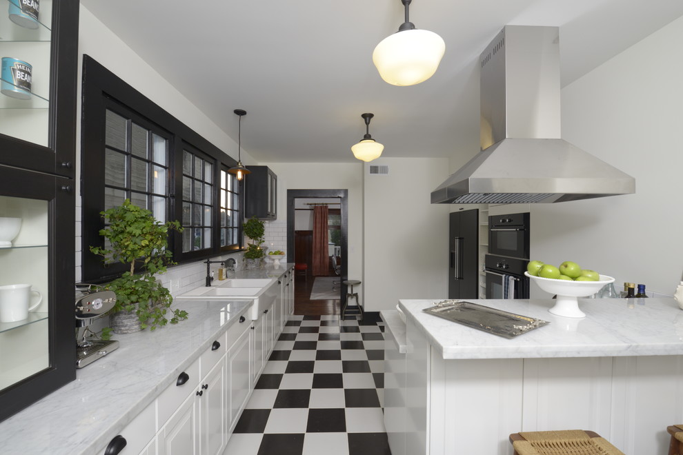 Design ideas for a large traditional u-shaped enclosed kitchen in Los Angeles with a breakfast bar, raised-panel cabinets, white cabinets, marble worktops, white splashback, metro tiled splashback, black appliances, a belfast sink and ceramic flooring.