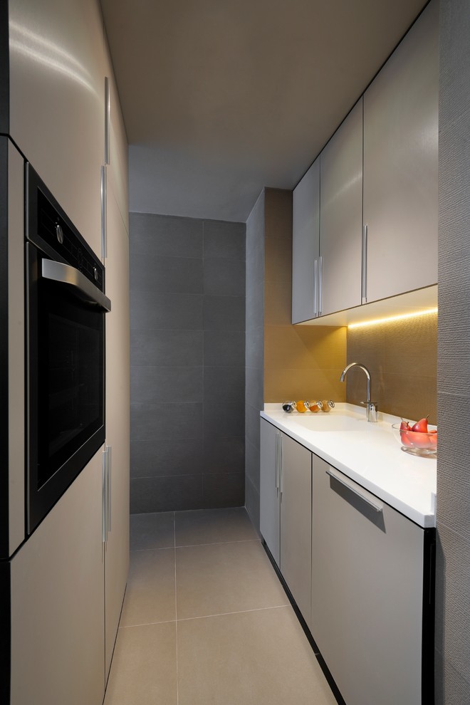 Cette photo montre une cuisine parallèle tendance fermée avec un placard à porte plane, des portes de placard grises et un électroménager en acier inoxydable.