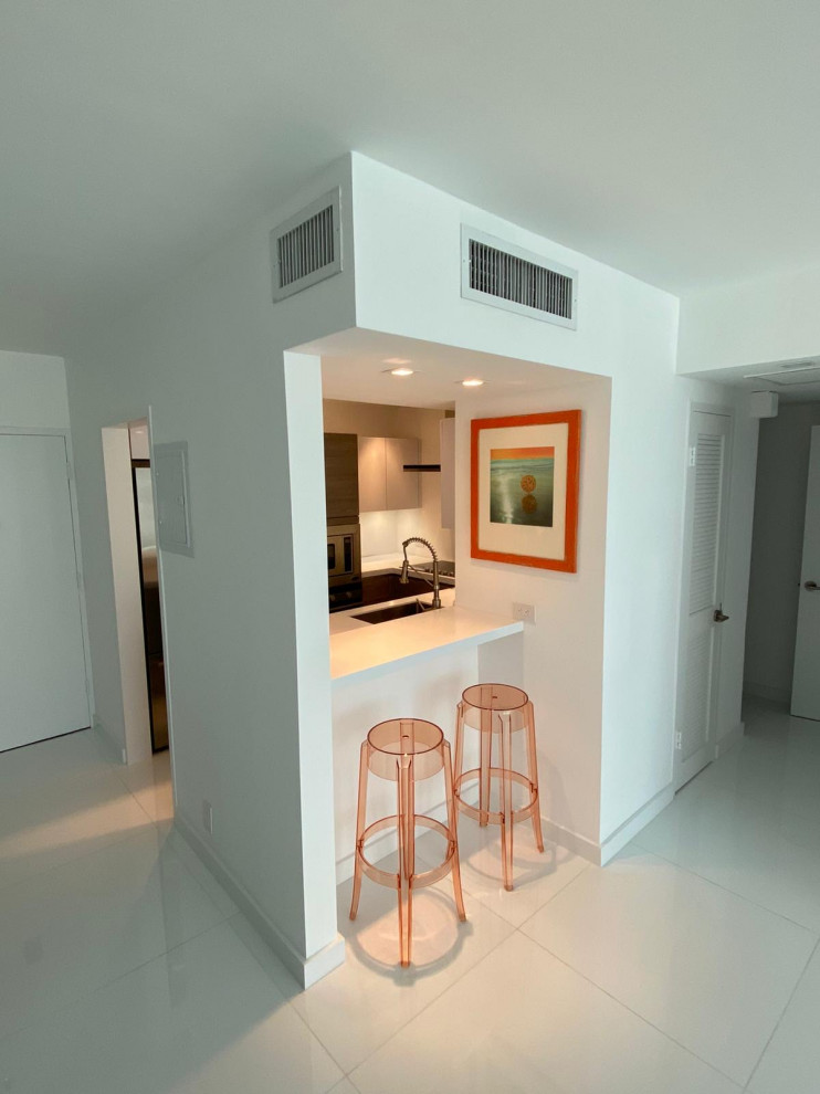 Example of a small u-shaped ceramic tile and white floor kitchen pantry design in Miami with a drop-in sink, flat-panel cabinets, white cabinets, quartz countertops, ceramic backsplash, stainless steel appliances and multicolored countertops
