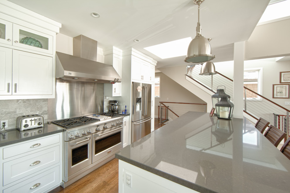 Eat-in kitchen - mid-sized coastal l-shaped medium tone wood floor and beige floor eat-in kitchen idea in Orange County with shaker cabinets, white cabinets, gray backsplash, stainless steel appliances, quartzite countertops, marble backsplash and an island