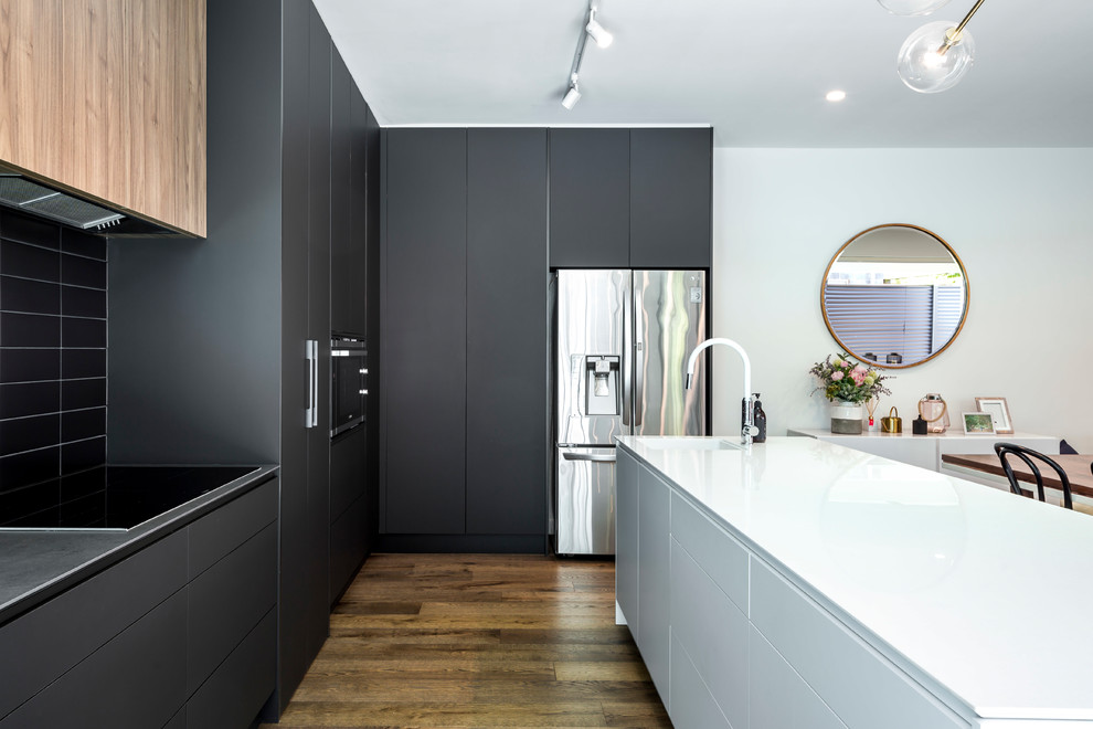 Immagine di un cucina con isola centrale design con ante nere e paraspruzzi nero